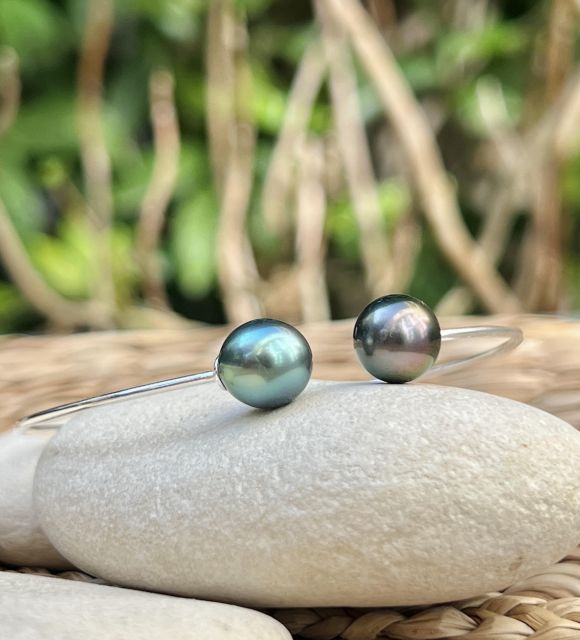 Deux perles de culture de Tahiti goutte, bleu lagon et peacock bronze, de 9,36 mm et 9,47 mm, qualité AAA et au lustre excellent, se répondent sur un jonc fin et discret.