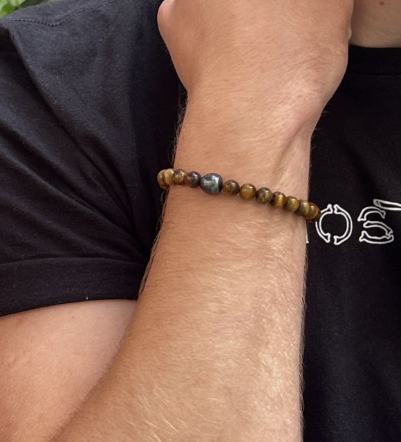 Черная жемчужина с голубыми отливами, как ночь, пронзенная вспышками души. Вокруг нее глаз тигра излучает тепло и защиту.