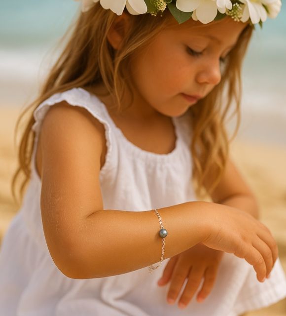 Une perle de Tahiti semi-baroque, de qualité A, comme un éclat venu du lagon, posée sur une chaîne d’argent pour accompagner les premiers instants de la vie.