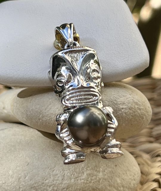 タヒチ産のドロップパール、深く神秘的なナス色が、ロジウム仕上げのシルバー製の守護ティキの中心に現れます。真正と保証の証明書付き。