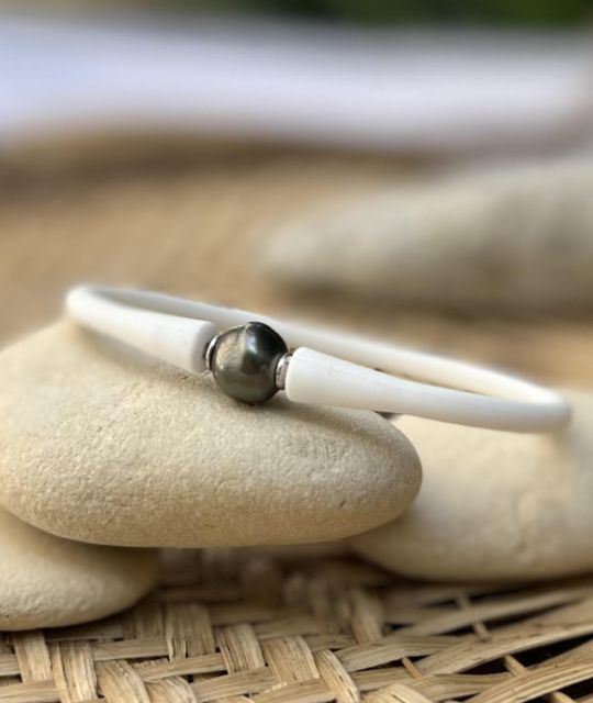 Zeigen Sie Ihren Charakter und Ihre Leidenschaft für Polynesien und sein Emblem, eine echte schwarze Tahiti-Perle, montiert auf einem weißen, gemischten Silikonarmband.