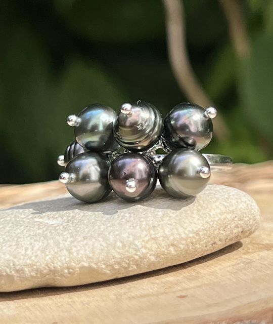 Bague en argent rhodié ornée de 7 perles de Tahiti Peacock aux reflets verts, bleus et aubergine. Un bijou élégant et contemporain inspiré des couleurs des lagons polynésiens.