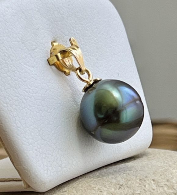 En or jaune 18 carats, ce pendentif met en lumière une perle de Tahiti ovale de 11,68 mm, d’un bleu rare oscillant entre lagon clair et profondeur océanique