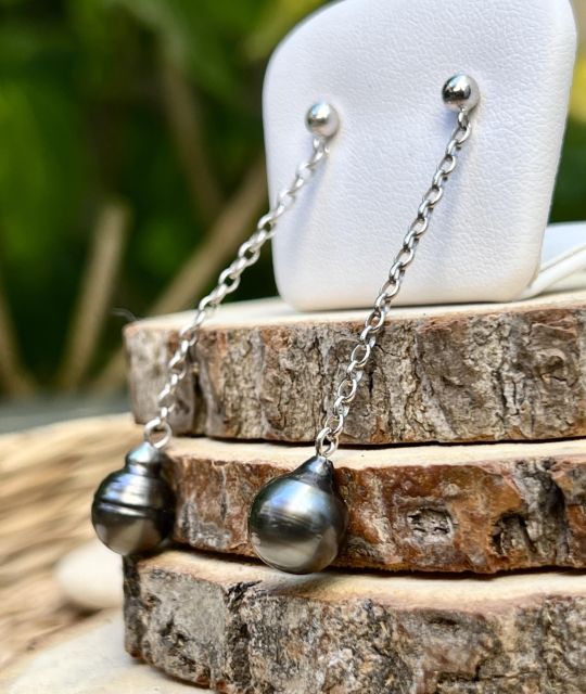 2 perles de Tahiti grises, comme deux éclats de lagon glissant le long d’un fil d’argent. Légères et lumineuses, elles dessinent la grâce à chaque mouvement.