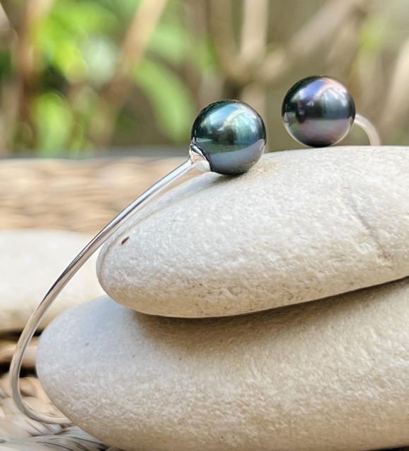 Deux perles de culture de Tahiti goutte, bleu lagon et peacock bronze, de 9,36 mm et 9,47 mm, qualité AAA et au lustre excellent, se répondent sur un jonc fin et discret.