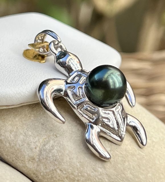 Une tortue en argent aux motifs marquisiens, symbole de protection et d’équilibre, abrite une perle noire de Tahiti ronde de 9.25 mm - livraison gratuite en UE