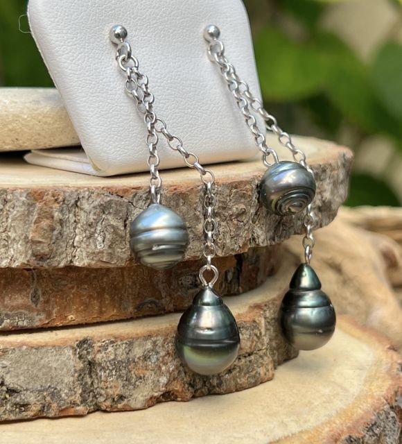 Gris satiné et peacock vibrant glissent sur un fil d’argent. Quatre perles suspendues comme des notes en apesanteur, pour un bijou qui danse avec la lumière.