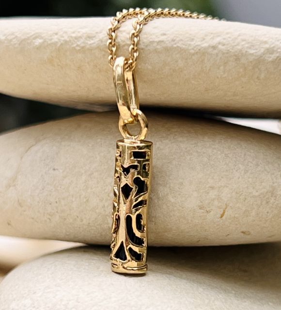 Le symbole de la force contenu dans un pendentif représentant le tiki Tahitien, en plaqué or jaune et onyx - livraison offete en Union Européenne