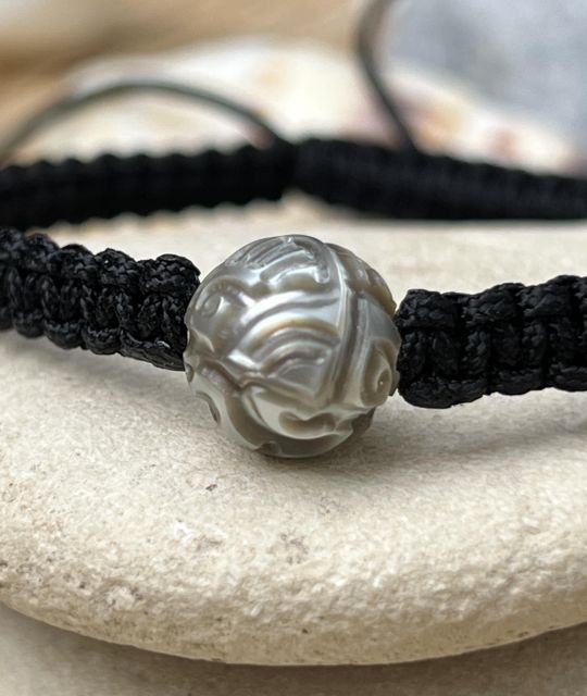Entdecken Sie die wunderschön gravierte, hellgraue Perle, die in unserem Atelier in Nantes auf einem geflochtenen Armband montiert wurde - zertifiziert und garantiert - schnelle Lieferung