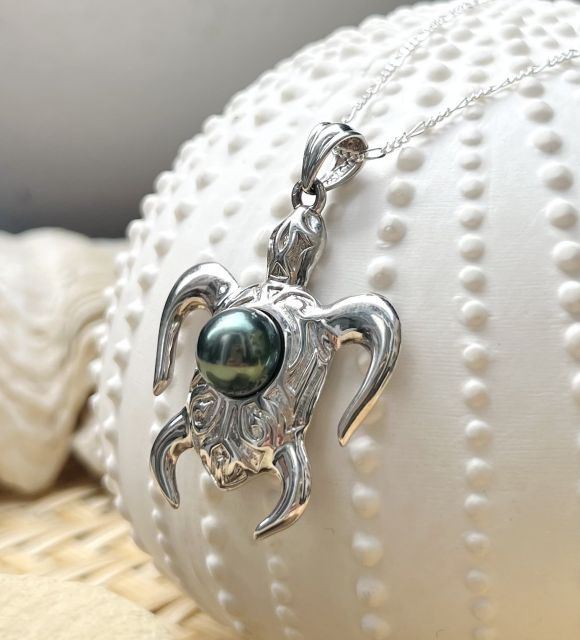 一颗颜色为开心果绿色、光泽亮丽的壮丽大溪地黑珍珠，搭配这款男性海龟吊坠，象征着波利尼西亚泻湖 - GIA认证