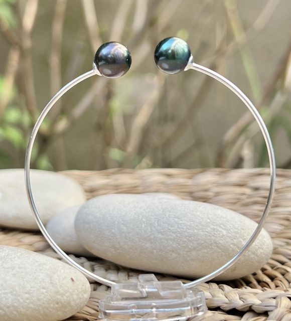 Deux perles de culture de Tahiti goutte, bleu lagon et peacock bronze, de 9,36 mm et 9,47 mm, qualité AAA et au lustre excellent, se répondent sur un jonc fin et discret.