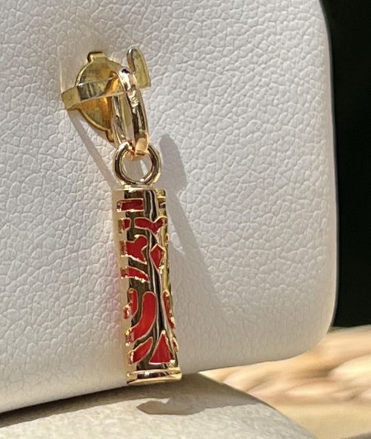 Pendentif en plaqué or et résine corail en forme de Tiki Tahitien : incarnation de la puissance et de la tradition polynésiennes