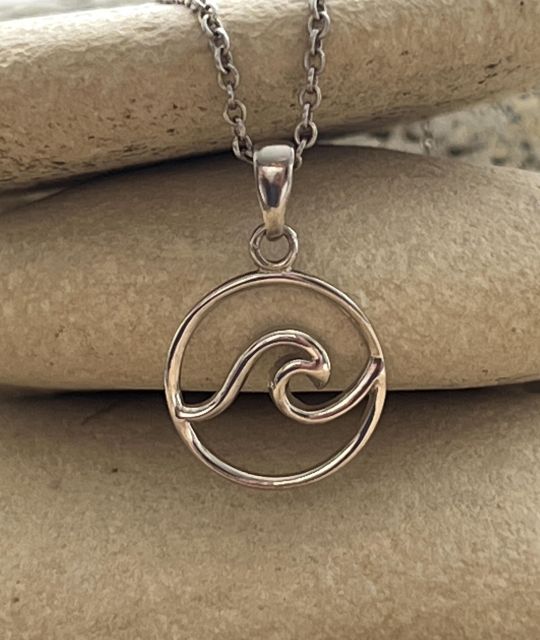 Übernehmen Sie den Moana-Anhänger aus rhodiniertem Silber, eine elegante Welle in einem Silberkreis. Ein Symbol für Freiheit und Gelassenheit, perfekt für Liebhaber des Ozeans.