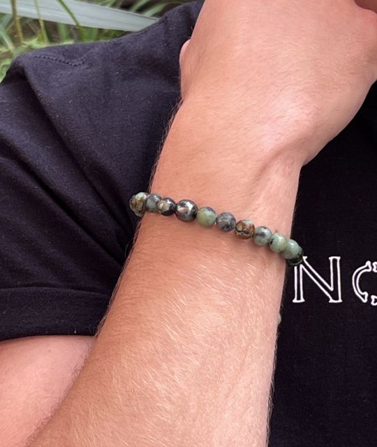 Im Zentrum eine tahitianische Perle mit einem Durchmesser von 9,85 mm, grün schimmernd, wie ein Sturmversprechen am Horizont der Lagune.