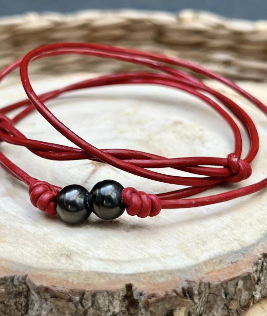 Zwei schwarze Perlen auf einem roten Band wie eine Glut. Ihr tiefer Glanz erzählt von den Tiefen der Lagune, ihre Spiegelungen tanzen wie Glut unter dem Mond.