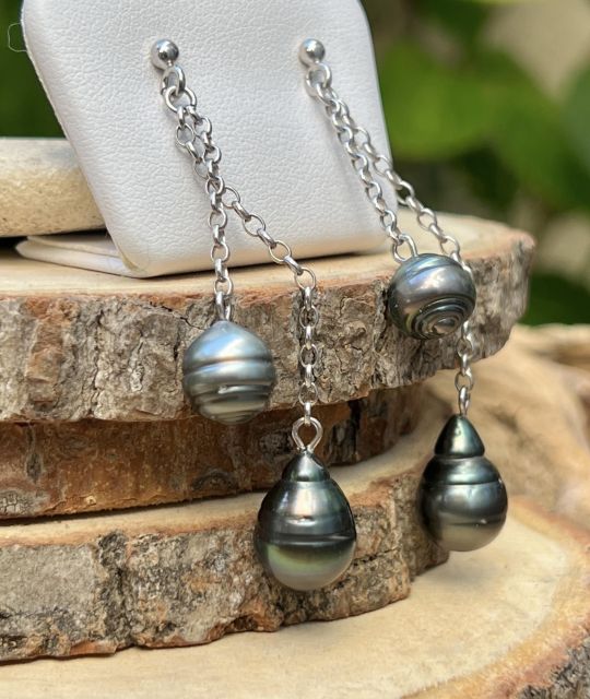 Gris satiné et peacock vibrant glissent sur un fil d’argent. Quatre perles suspendues comme des notes en apesanteur, pour un bijou qui danse avec la lumière.