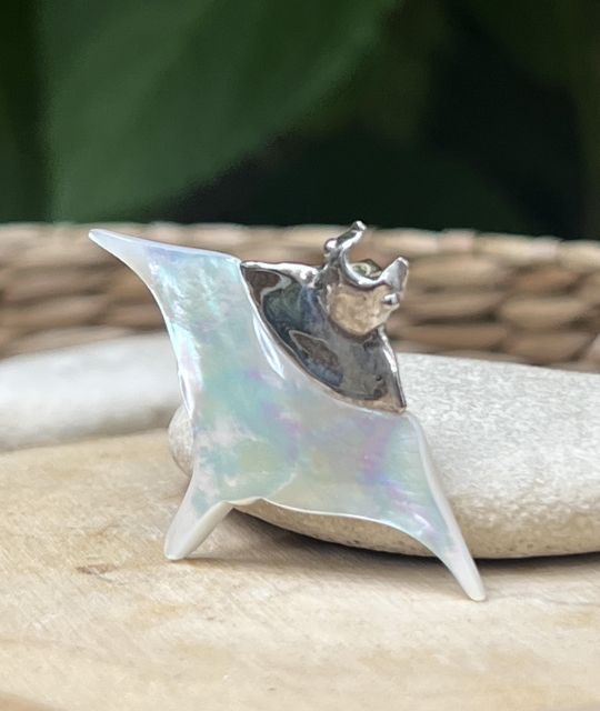 Pendentif raie manta en nacre blanche et argent rhodié, inspiré par les lagons polynésiens. Un bijou symbolique, aérien et lumineux.