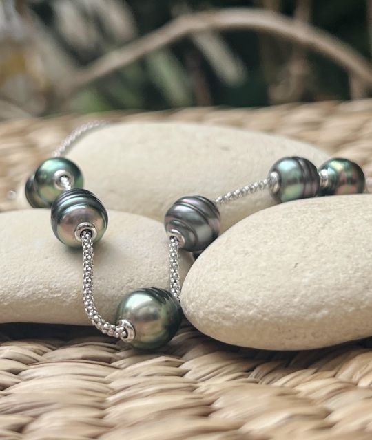 Sieben Tahiti-Perlen tanzen auf einem Silbergeflecht. Seltene und leuchtende Nuancen: ein Feuerwerk aus Farben, strahlend wie ein polynesisches Fest.