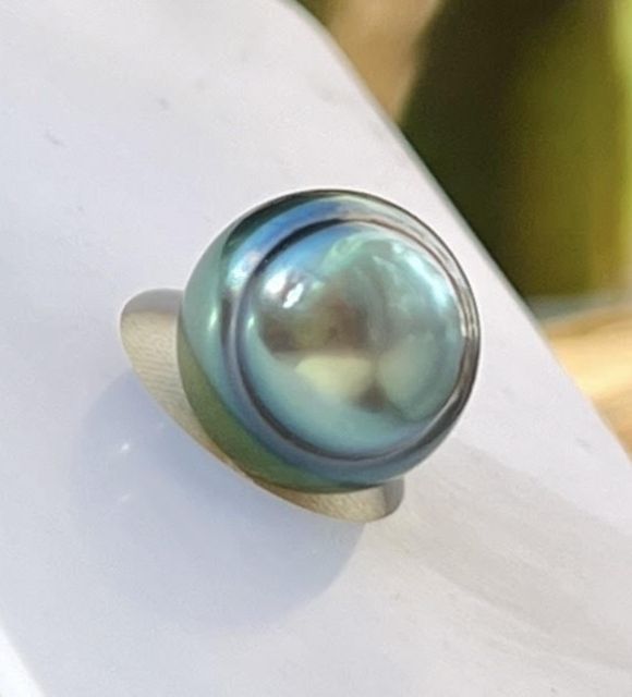 Une perle de culture de Tahiti cerclée sélection, au lustre excellent, dont la teinte unique mêle un rose délicat à un bleu lagon envoûtant