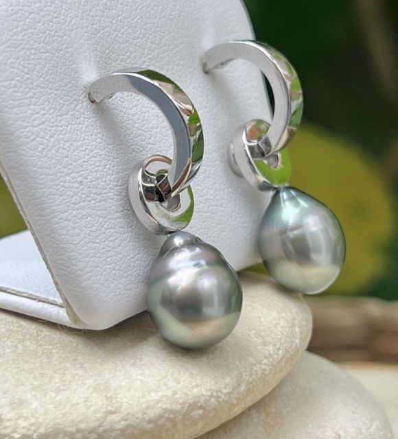 Un círculo de plata que danza, una perla suspendida como un aliento de luz. Con reflejos rosados y verdes laguna, cada perla evoca una puesta de sol polinesia.