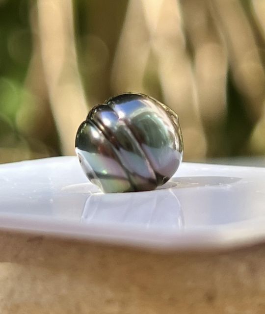 Eine gekreiste Tahiti-Perle mit hervorragendem Glanz, 9,00 mm im Durchmesser, deren blau-aubergine Farbe die ganze Tiefe der polynesischen Nacre offenbart.