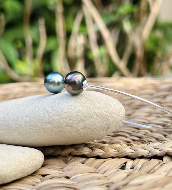Two cultured Tahitian drop pearls, lagoon blue and peacock bronze, measuring 9.36 mm and 9.47 mm, of AAA quality with excellent lustre, complement each other on a fine and discreet bangle.