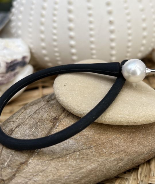 Entdecken Sie unser schwarzes Silikonarmband mit einer weißen Süßwasserperle. Modernes und schlichtes Design, perfekt für einen modernen und eleganten Look.