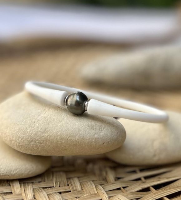 あなたの個性と、ポリネシアおよびその象徴を表現するために、白いシリコンミックスのブレスレットにセットされた本物のタヒチの黒真珠をご覧ください。