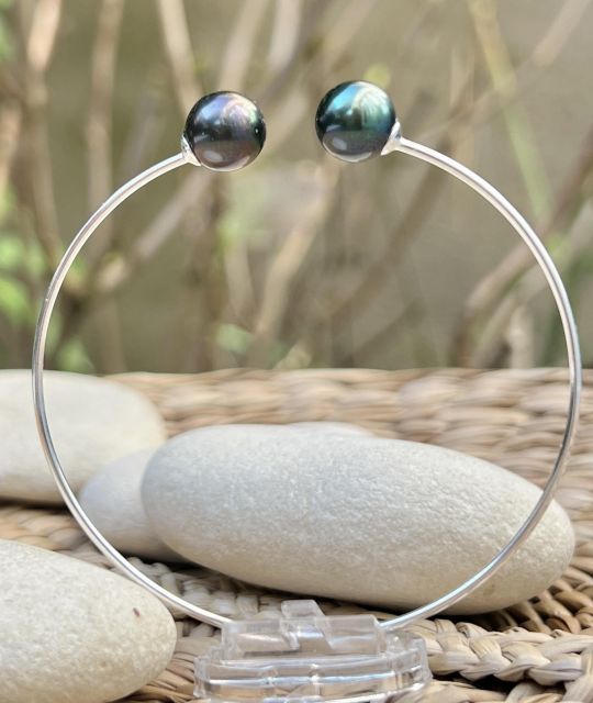 Deux perles de culture de Tahiti goutte, bleu lagon et peacock bronze, de 9,36 mm et 9,47 mm, qualité AAA et au lustre excellent, se répondent sur un jonc fin et discret.