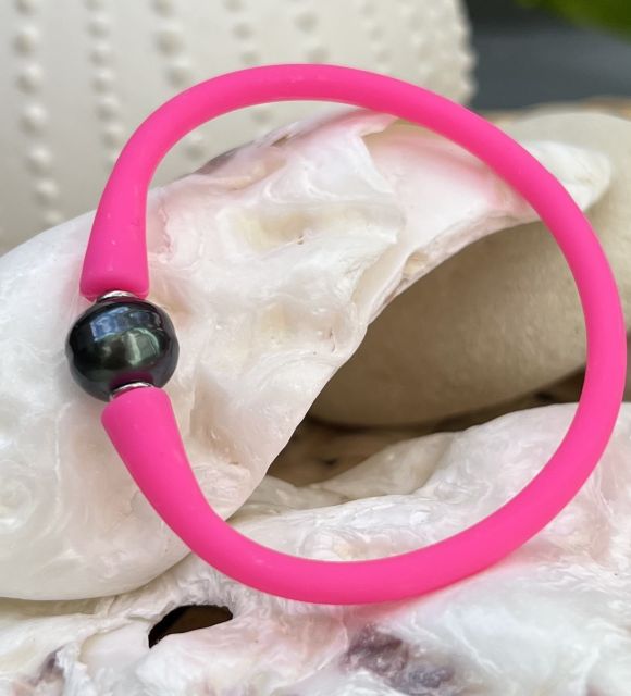 Un éclatant bracelet en silicone rose fluo orné d'une sombre perle de Tahiti noire
