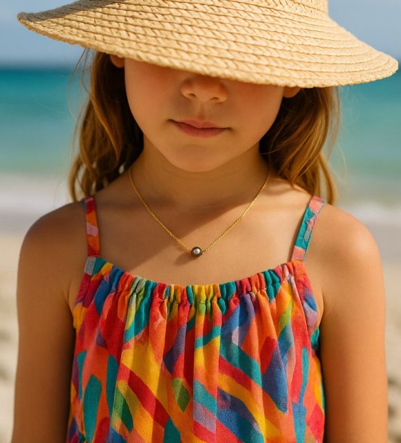 Une perle de Tahiti, ronde et lumineuse, glisse sur un fil d’or fin comme un rayon de soleil. Un collier perle pour enfant, délicat comme une promesse, précieux comme l’enfance.