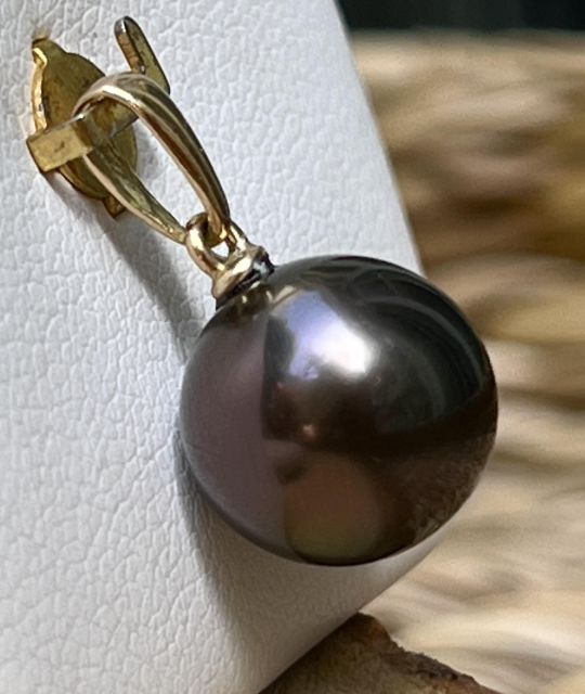 Découvrez Aura, un pendentif en or 18 carats sublimé par une véritable perle de Tahiti aubergine AAA+ de 11.03 mm au lustre exceptionnel. Une création joaillière lumineuse et raffinée signée Poemotu.