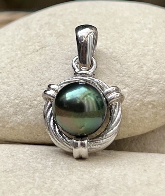 Ein maskulines Schmuckstück, dezent und kraftvoll. Aus rhodiniertem Silber gefertigt, trägt es eine runde Tahiti-Perle (9/10 mm), AA-Qualität, mit intensivem Glanz und Pfauen-, schwarzen oder grauen Schattierungen.