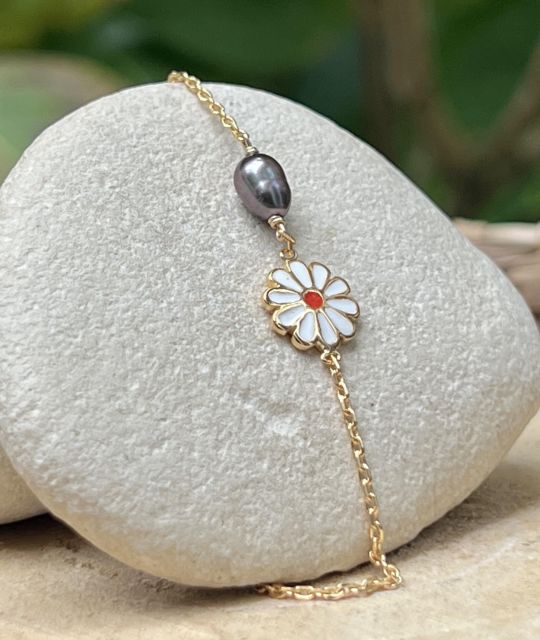 Hinara célèbre la douceur de l’enfance avec un keshi de Tahiti rose bleuté, comme une caresse de lagon, et une fleur au cœur joyeux.