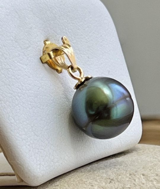 En or jaune 18 carats, ce pendentif met en lumière une perle de Tahiti ovale de 11,68 mm, d’un bleu rare oscillant entre lagon clair et profondeur océanique