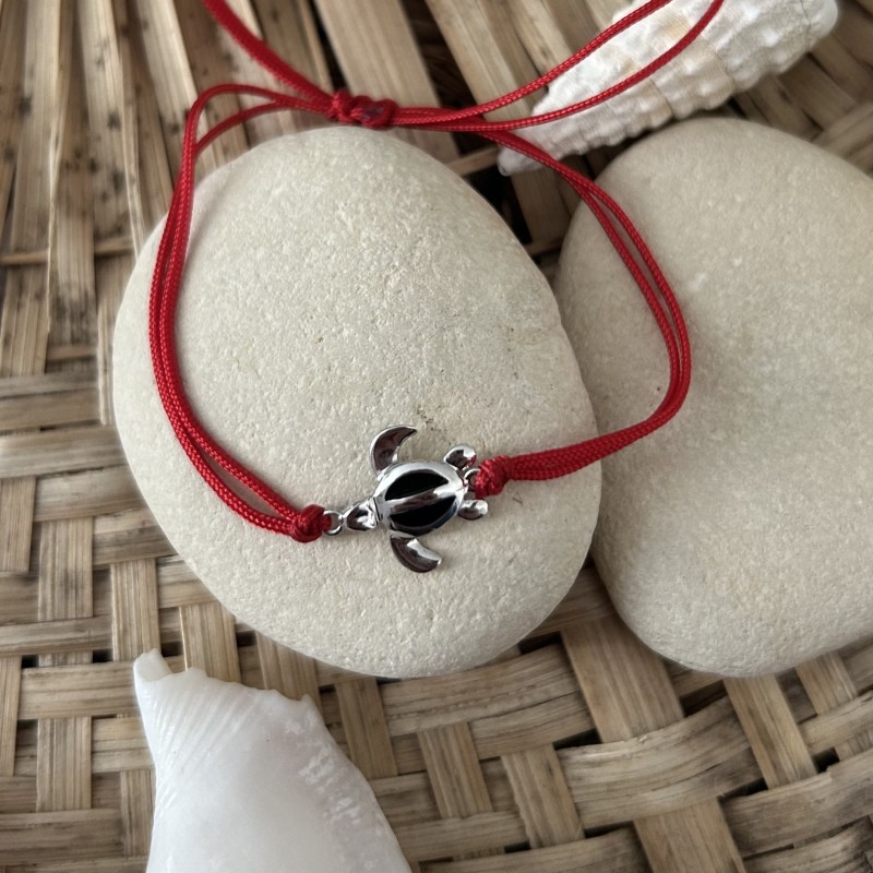 赤いコットンブレスレットと銀のカメと黒のエナメル